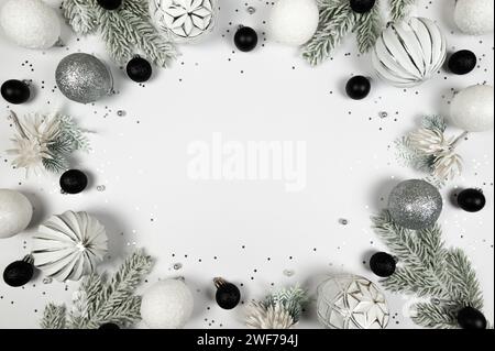 Weihnachtskomposition, weiße und silberne Dekorationen, schwarze Kugeln, Tannenzweige, silberne Sterne Konfetti auf weißem Hintergrund. Stockfoto