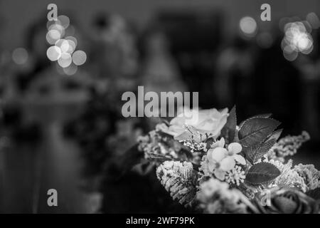 Die Graustufen-Aufnahme eines Blumenaufsatzes mit zartem Frost und sanfter Bokeh-Beleuchtung verleiht dem Herzstück eine klassische Eleganz Stockfoto