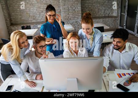 Lächelnde Gruppe von verschiedenen Geschäftsleuten, die zusammen an einem Besprechungstisch in einem Büro arbeiten Stockfoto