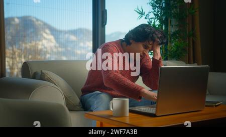 Männliche sitzen auf dem Sofa, leiden Schmerzen in der Brust, haben Herzinfarkt, halten die Brust massieren, während sie mit dem Laptop arbeiten. Männlicher Atembeschwerden Schlaganfall zu Hause. Stockfoto