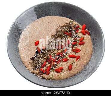 Leinbrei in einer Schüssel, gesundes Frühstück oder Snack, Brei dekoriert mit Chia Samen und Goji Beeren auf weißem isolierten Hintergrund Stockfoto