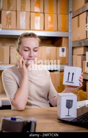 Frau, die ein Mobiltelefon oder Tablet verwendet, um mit Kunden zu kommunizieren. Lieferung von Waren über private Kurierdienste. Konzepte des Online-Verkaufs und weiter Stockfoto