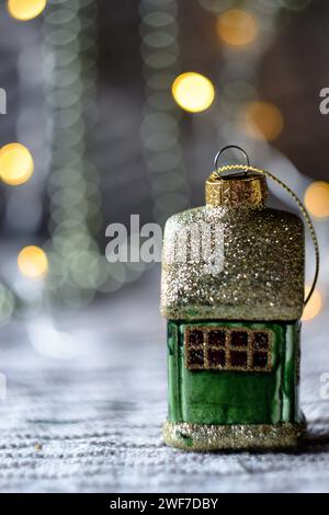 Weihnachtsbaumspielzeug in Form eines Hauses vor dem Hintergrund eines Bokeh aus Girlanden Stockfoto