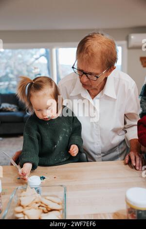 Urgroßmutter und Enkelin, die Kekse zuckern, Küchenfreude Stockfoto