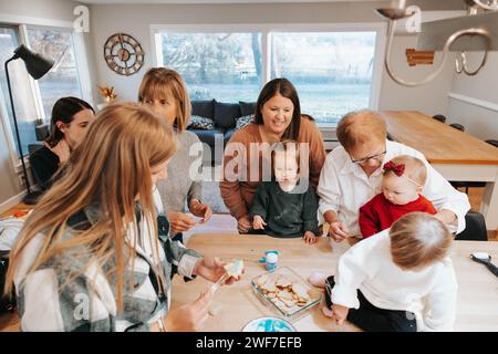 Große Familie liebt es, Zuckerkekse zu dekorieren, Küchenfreude Stockfoto