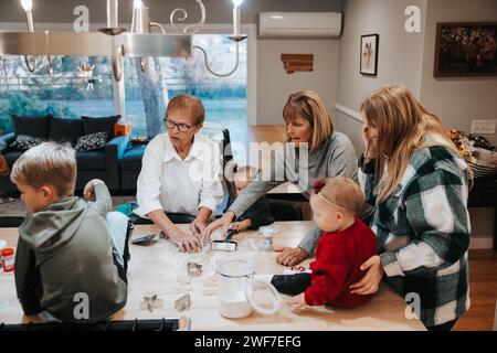 Drei Generationen schneiden Zuckerkekse aus, Küchengenuss Stockfoto