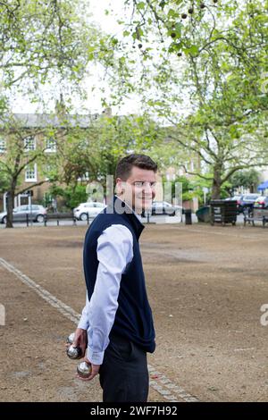 Junge Männer spielen Boules in einem kleinen offenen Raum in London, England Stockfoto