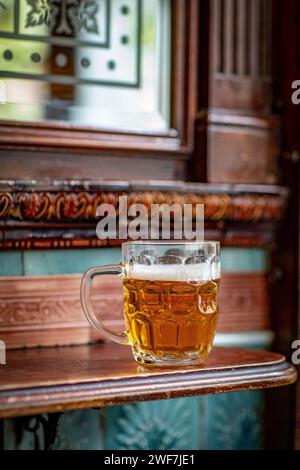 Britisches Pint-Dimple-Becher mit Bier steht auf dem Tisch im Pub Stockfoto