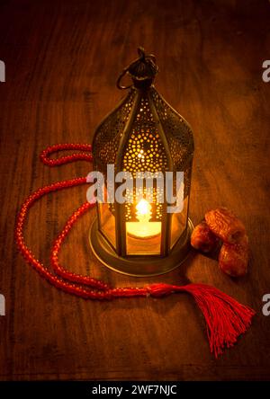 Eine wunderschöne beleuchtete Ramadan-Lampe mit wenigen Datteln und islamischem Rosenkranz. Traditionelle Ramadan-Lampe. Stockfoto