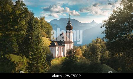 Idyllische kleine Kirche im Herzen der Natur, malerische deutsche Alpenlandschaft in Berchtesgaden mit Bergen im Hintergrund, blauem Himmel und üppigen Bäumen Stockfoto