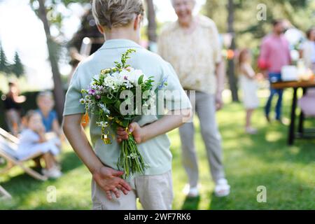Schöne ältere Geburtstagsfrau, die Blumen von Enkelkindern erhält. Konzept des Gartengeburtstages für ältere Frauen. Stockfoto