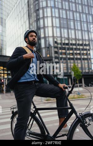 Pendler in der Stadt, Geschäftsmann, der mit dem Fahrrad von der Arbeit nach Hause reist, Rucksack und Helm trägt, um Sicherheit zu gewährleisten. Städtischer Lebensstil des alleinstehenden Mannes. Stockfoto