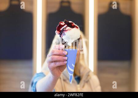 Die Frau hält Eisbecher vor ihr Gesicht, weicher Fokus Stockfoto