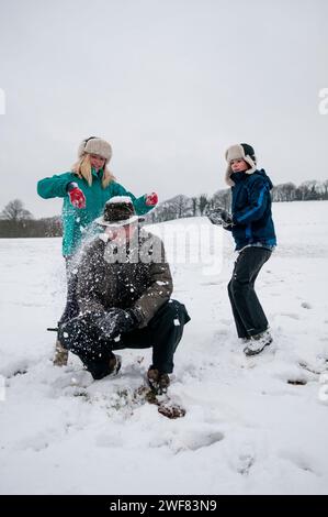 Eine Familie spielt Schneeballschlachten in einer verschneiten Winterlandschaft. Stockfoto