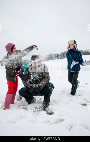 Eine Familie spielt Schneeballschlachten in einer verschneiten Winterlandschaft. Stockfoto