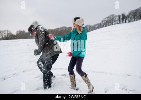 Eine Familie spielt Schneeballschlachten in einer verschneiten Winterlandschaft. Stockfoto