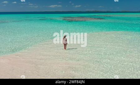 Tropischer Inselstrand mit Korallenriff kristallklarem türkisfarbenem Wasser. Frau zurück Blick im Meer stehend genießen Sie wunderschöne wilde Naturlandschaft. Gelbes Kajak. Sommerferien. D Stockfoto