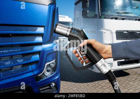 Hand mit H2-Kraftstoffdüse auf einem Hintergrund eines Wasserstoff-Brennstoffzellenfahrzeugs. Umweltfreundliches Nutzfahrzeugkonzept. Stockfoto