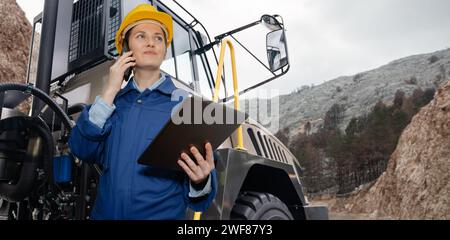 Eine Ingenieurin mit Tablet-Computer steht auf der Treppe zum Fahrerhaus eines Lastwagens Stockfoto