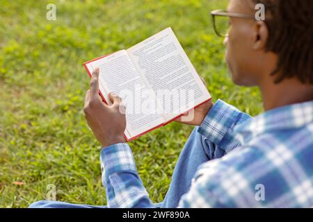 Rückansicht eines schwarzen Studenten, der draußen ein Buch liest Stockfoto