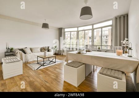 Ein modernes und geräumiges Wohnzimmer verbindet sich nahtlos mit einem Essbereich, der durch große Fenster mit Tageslicht durchflutet wird. Stockfoto