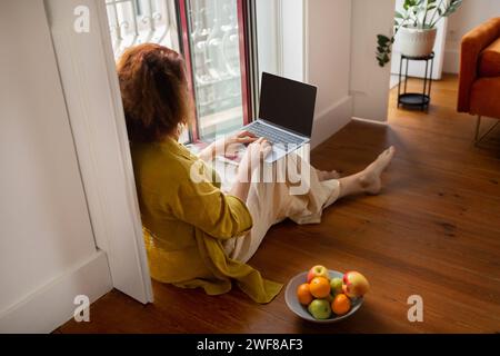 Konzentrierte Seniorin, die zu Hause einen Laptop mit leerem Bildschirm benutzt Stockfoto