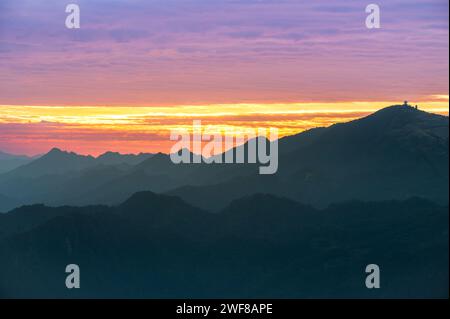 Silhouetten der Berge im goldenen Sonnenuntergang. Sich bewegende Wolken am orangefarbenen Himmel. Warme Winterlandschaft im Norden Taiwans, Shuangxi Buyanting Pavillon. Stockfoto