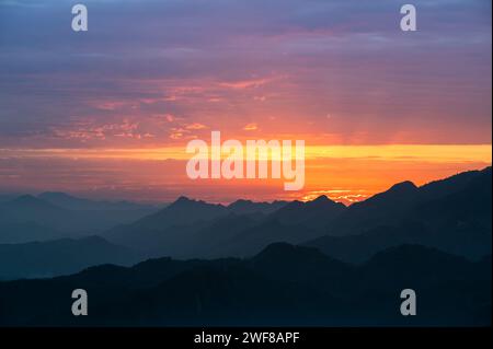 Silhouetten der Berge im goldenen Sonnenuntergang. Sich bewegende Wolken am orangefarbenen Himmel. Warme Winterlandschaft im Norden Taiwans, Shuangxi Buyanting Pavillon. Stockfoto