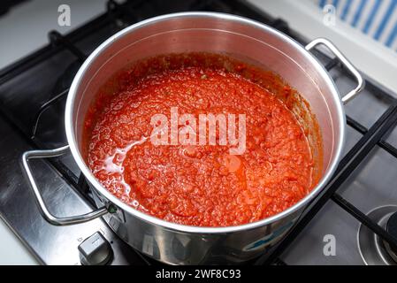 Roter Tomatensoße nach neapolitanischer Art wird in einem Topf auf einem Kochfeld gekocht, Blick von oben. Tomaten-Ragout-Fleisch in einem Stahltopf Stockfoto