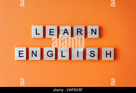Word Englisch lernen. Motivation. Der Satz ist in Holzbuchstaben von oben angeordnet. Motivation. Orangefarbener flacher Lay-Hintergrund Stockfoto