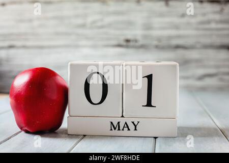 Kalenderblöcke aus weißem Holz mit dem Datum des 1. Mai und einem roten Apfel für den Nationallehrertag. Stockfoto
