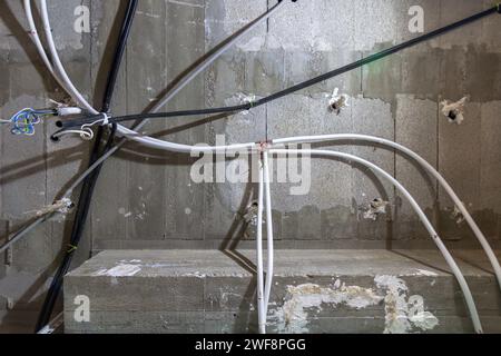 Unfertige Decke mit sichtbaren Elektro- und Sanitärinstallationen auf einer Baustelle eines neuen Hauses. Bauarbeiten Stockfoto