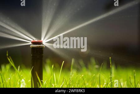 Automatische Sprinkleranlage zur Bewässerung des Rasens auf dunklem Hintergrund Nahaufnahme Stockfoto