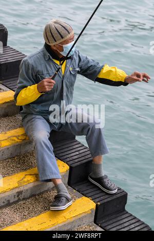 26. Januar 2024, Hongkong, SVR Hongkong, China: Ein einheimischer Fischer in Victoria Harbour Central Harbourfront, Hongkong, landet einen kleinen Fisch zum Abendessen. (Kreditbild: © Jayne Russell/ZUMA Press Wire) NUR REDAKTIONELLE VERWENDUNG! Nicht für kommerzielle ZWECKE! Stockfoto