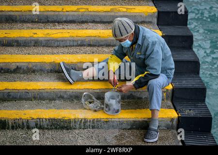 26. Januar 2024, Hongkong, SVR Hongkong, China: Ein einheimischer Fischer in Victoria Harbour Central Harbourfront, Hongkong, landet einen kleinen Fisch zum Abendessen. (Kreditbild: © Jayne Russell/ZUMA Press Wire) NUR REDAKTIONELLE VERWENDUNG! Nicht für kommerzielle ZWECKE! Stockfoto