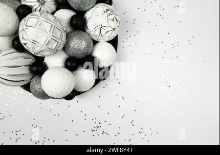 Weihnachtskomposition, Tannenschmuck, weiße, silberne und schwarze Kugeln, silberne Sterne Konfetti auf weißem Hintergrund. Stockfoto