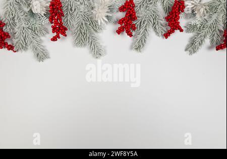 Weihnachtskomposition, Tannenzweige, weiße Blumen, rote Beeren auf weißem Hintergrund. Weihnachten, Neujahr, Winterkonzept. Stockfoto