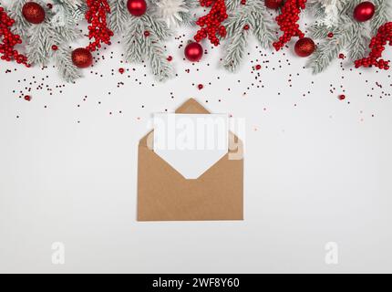 Weihnachtskomposition, Kraftumschlag, Tannenzweige, rote Beeren, Kugeln und Sterne Konfetti auf weißem Hintergrund. Stockfoto