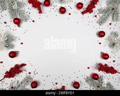 Weihnachtskomposition, Tannenzweige, rote Beeren, Kugeln und Sterne Konfetti auf weißem Hintergrund. Weihnachten, Neujahr, Winterkonzept. Stockfoto