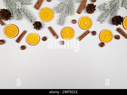 Weihnachtskomposition, getrocknete Orangenscheiben, Tannenzweige, Zimtstangen, Tannenzapfen, Haselnüsse auf weißem Hintergrund. Stockfoto