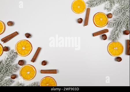 Weihnachtskomposition, getrocknete Orangenscheiben, Tannenzweige, Zimtstangen, Haselnüsse auf weißem Hintergrund. Weihnachten, Neujahr, Winterkonzept. Stockfoto