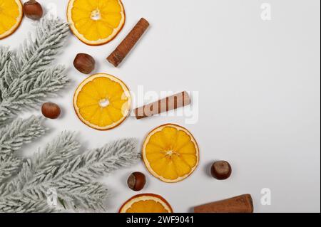 Weihnachtskomposition, getrocknete Orangenscheiben, Tannenzweige, Zimtstangen, Haselnüsse auf weißem Hintergrund. Weihnachten, Neujahr, Winterkonzept. Stockfoto