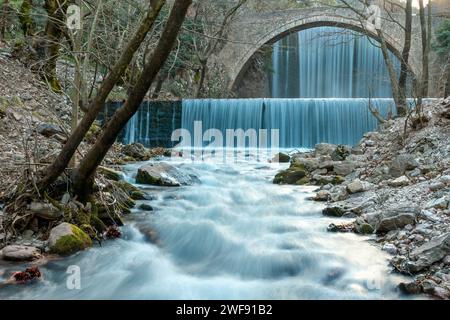 Eine alte Steinbrücke mit großem Bogen, zwischen zwei Wasserfällen in Paleokarya, Präfektur Trikala, Thessalien, Griechenland Stockfoto