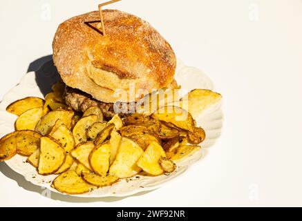 Portugiesischer hausgemachter Hamburger serviert mit rustikalen Kartoffeln, die verzehrt werden Stockfoto