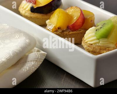 Zwei zierliche weiße Tabletts mit köstlichem Obstgebäck und frisch gebackenem Brot Stockfoto