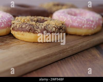 Verschiedene Donuts mit verschiedenen Geschmacksrichtungen auf einem rustikalen Holzschneidebrett Stockfoto