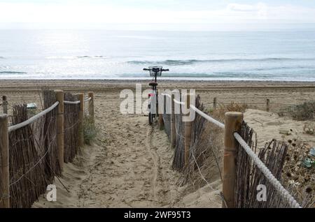 Das Fahrrad parkte am hölzernen Handlauf am einsamen Strand in Marbella, Andalusien, Spanien. Stockfoto