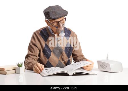 Älterer Mann, der einen Vernebler benutzt und ein Buch auf weißem Hintergrund liest Stockfoto