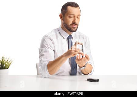 Geschäftsmann pickt Finger und überprüft den Blutzuckerspiegel isoliert auf weißem Hintergrund Stockfoto