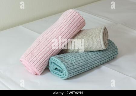 Mikrofaser-Reinigungstücher in Pink, Beige und Grün auf einem Tisch, bereit zur Reinigung. Weißer Hintergrund Stockfoto